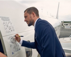 Islandsk fodboldspiller skriver sin autograf på Icelandairs Boeing 757-fly før afrejsen til Frankrig. (Foto: Icelandair)